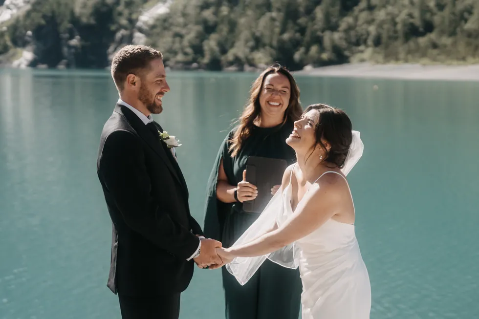 Lachendes Brautpaar an einem Bergsee